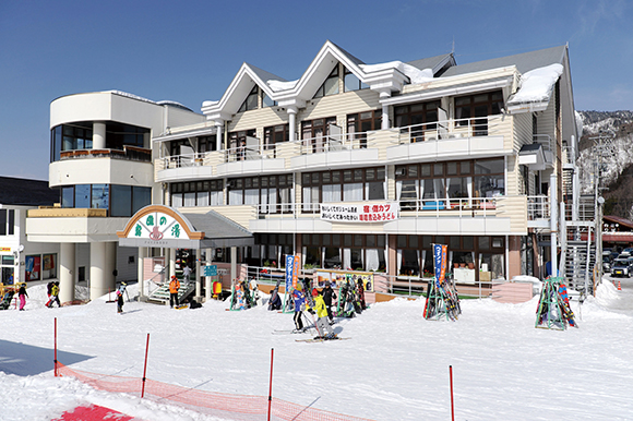 雪のゲレンデの前に建つ「ジョイフル朴の木」の建物全体