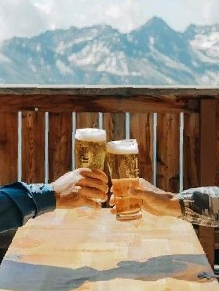 山を望むテラスでビールで乾杯する手元