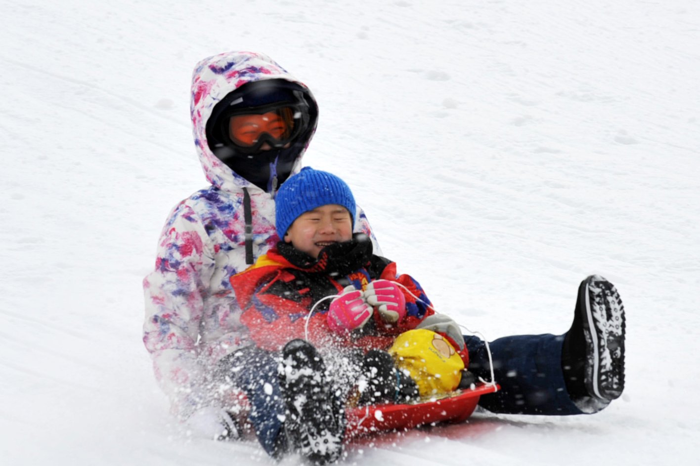 ソリで雪遊びを楽しむ子ども